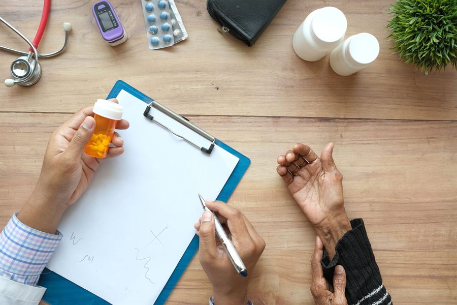 Doctor holding a pill bottle and writing notes