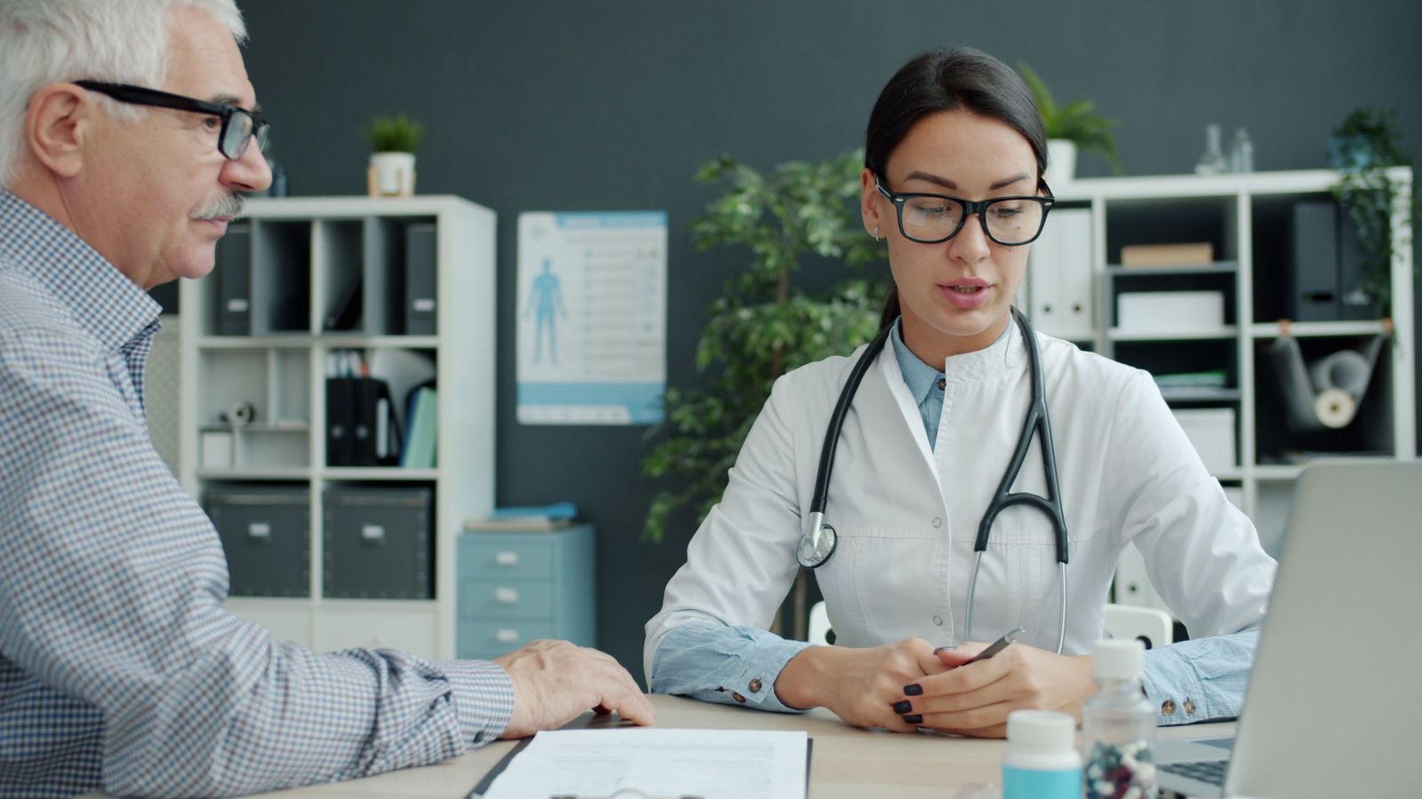Doctor talking with an older man at a desk before a trip